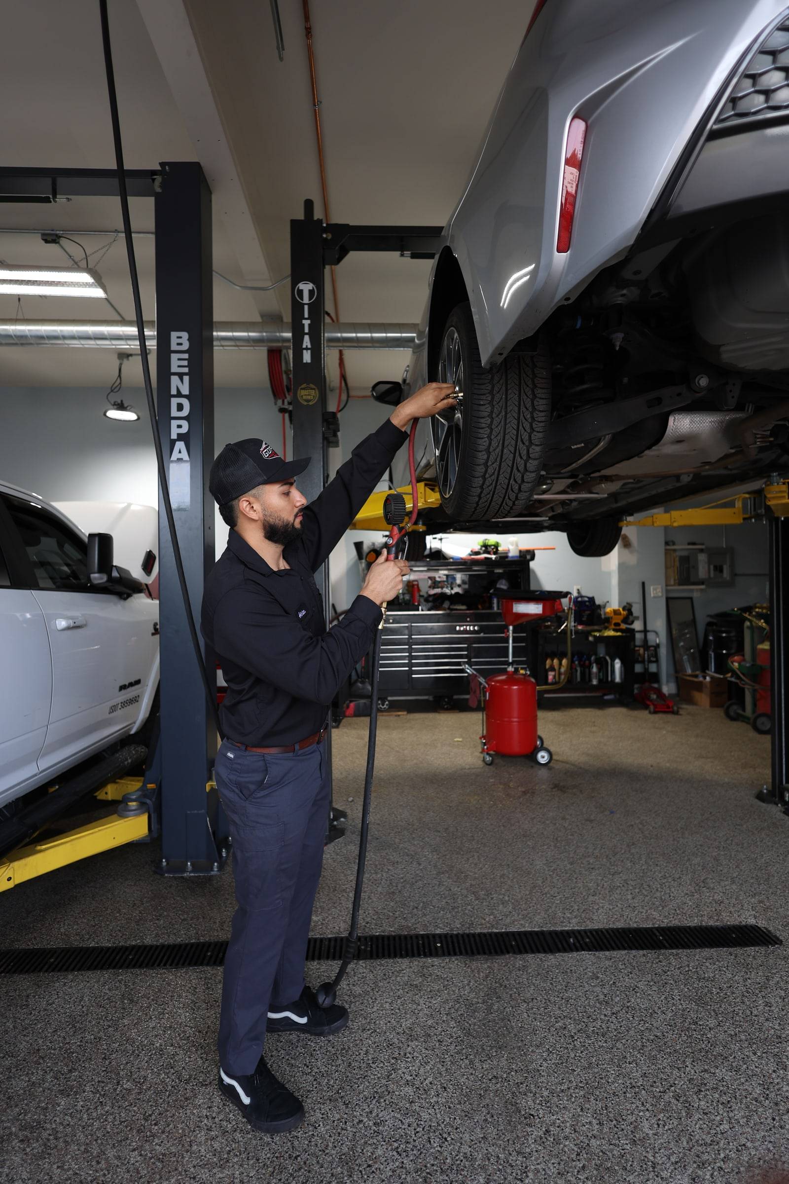 The lead tech at the rear wheel of a car up on the lift