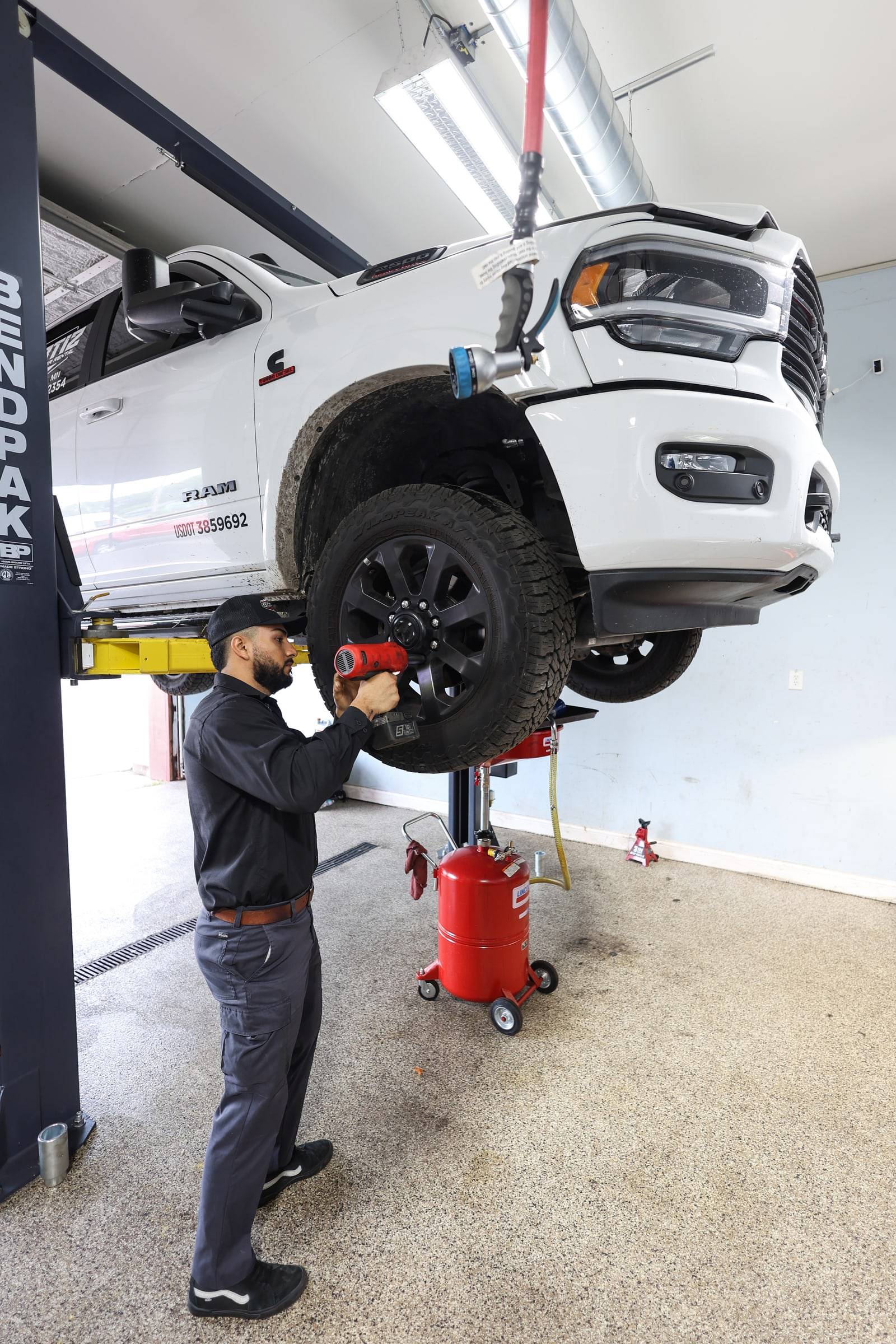 The lead tech at the front wheel hub of a pickup raised on the lift