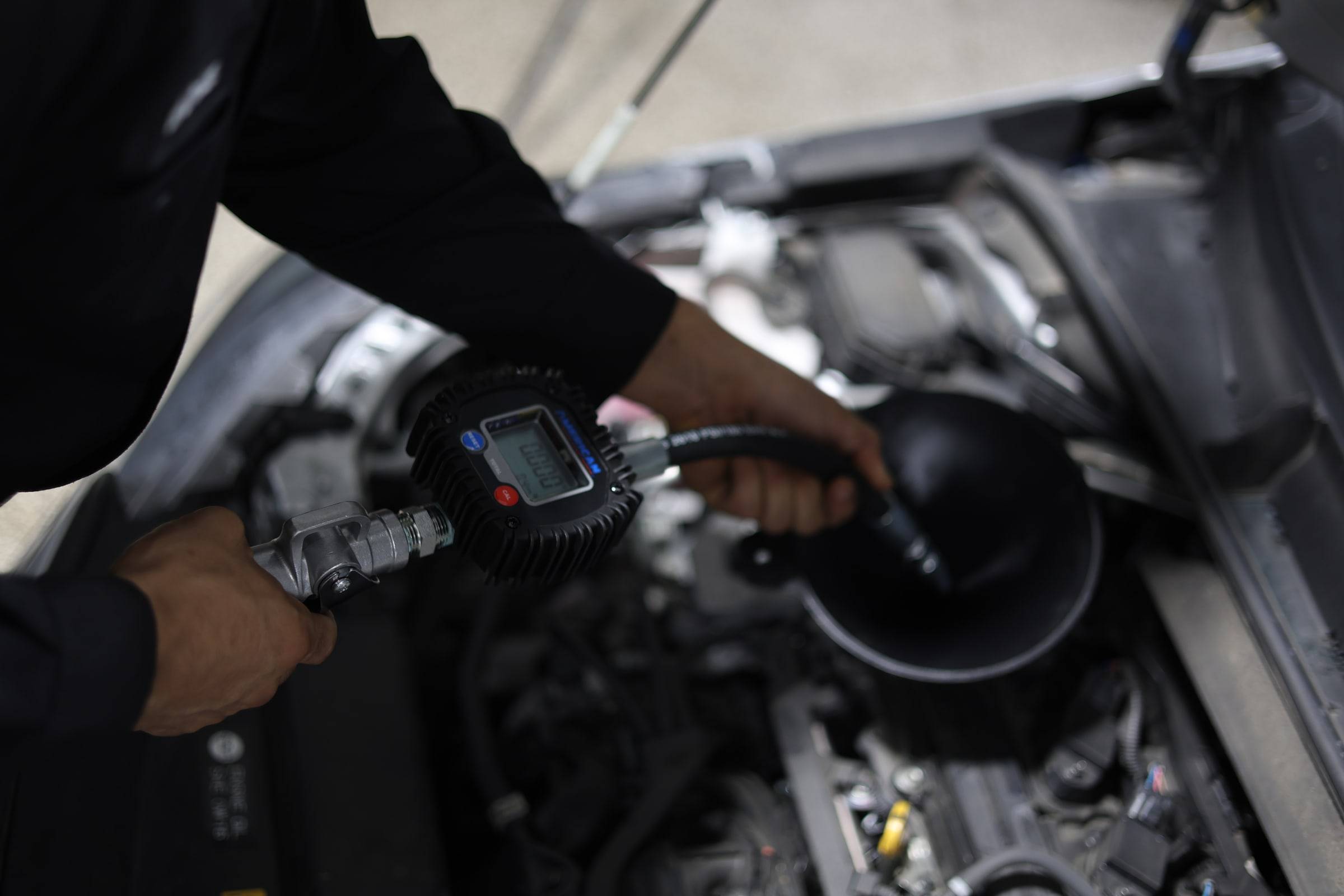 Close-up of oil going into an engine through a metered nozzle
